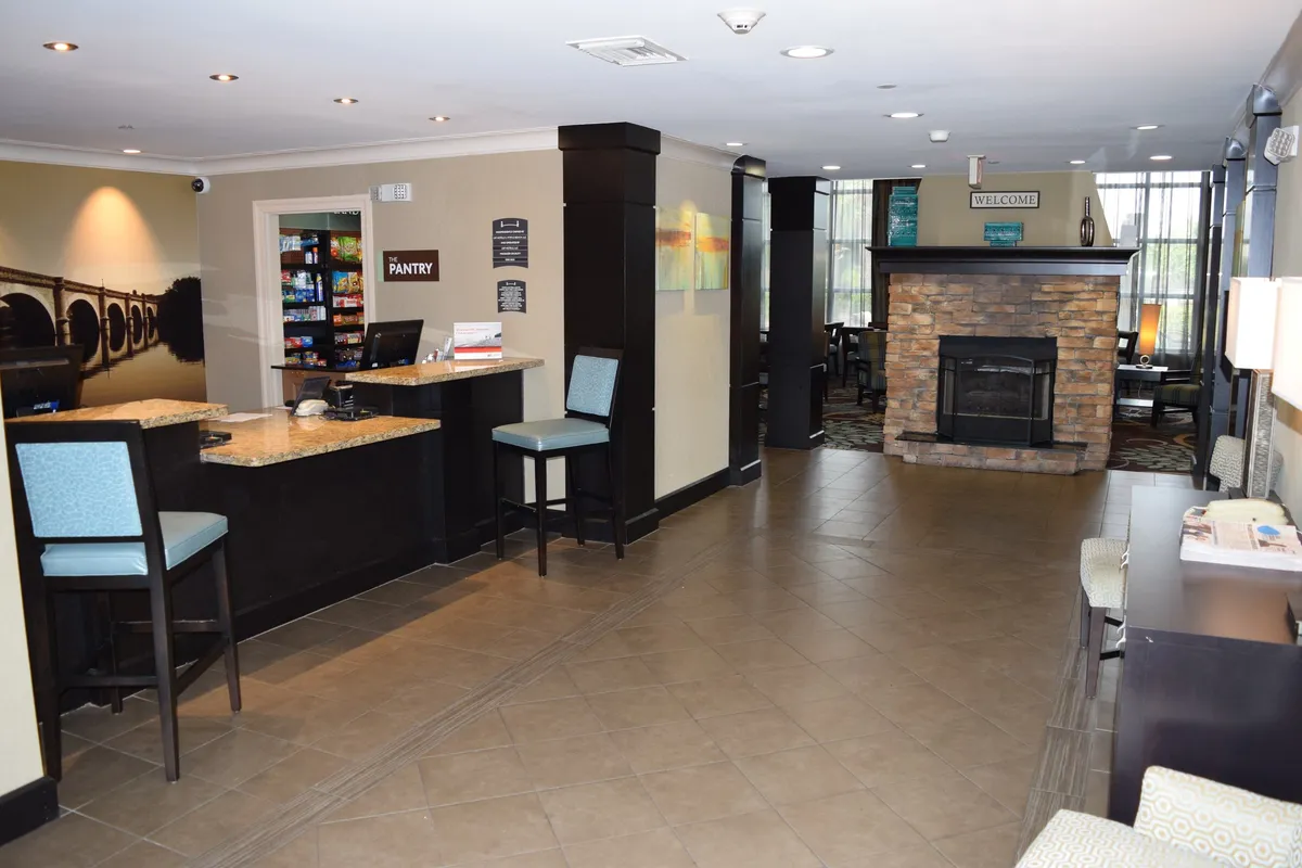 A cozy interior scene featuring the welcoming reception desk, a glowing fireplace, and a pantry area stocked with snacks. The inviting setting is perfect for guests arriving for their extended stay, offering comfort and seamless service.