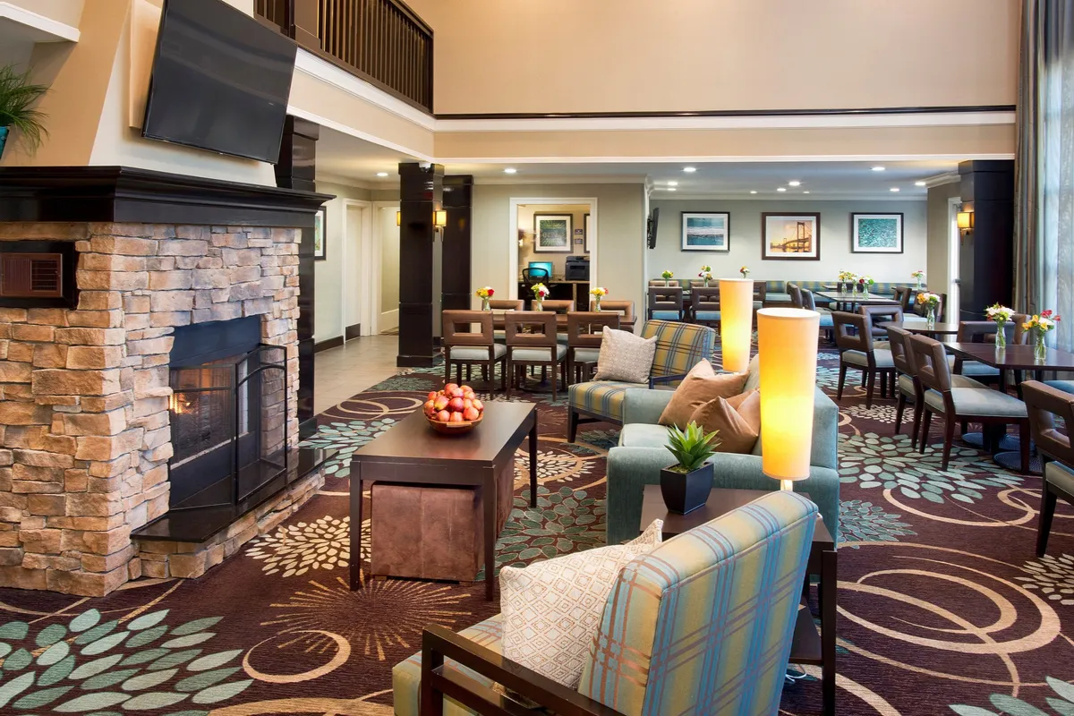 An inviting lounge area featuring a fireplace, cozy seating, dining tables, and decorative art. The arrangement encourages both social interaction and quiet relaxation, with a welcoming atmosphere accentuated by warm lighting.
